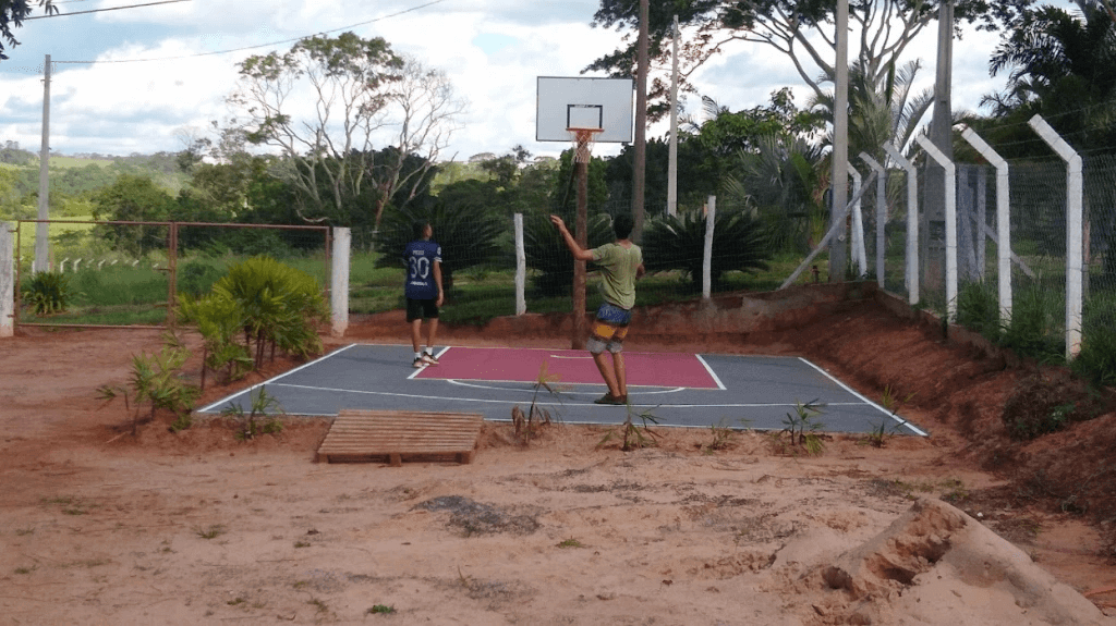 João e Pedro jogando basquete na quadra com tabela e aro a 2,90 metros de altura.