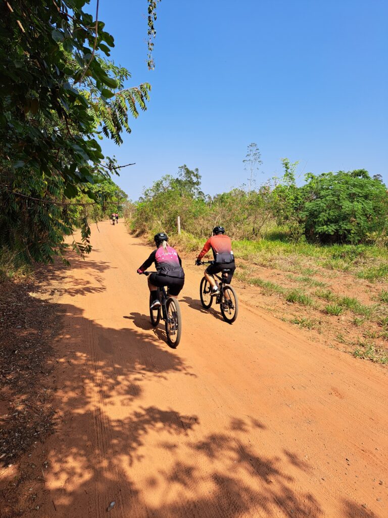 Pais de Laurinha em perfeita sintonia, pedalam de costas, celebrando a beleza da natureza e a alegria de estarem juntos na Trilha do Bezerrão.