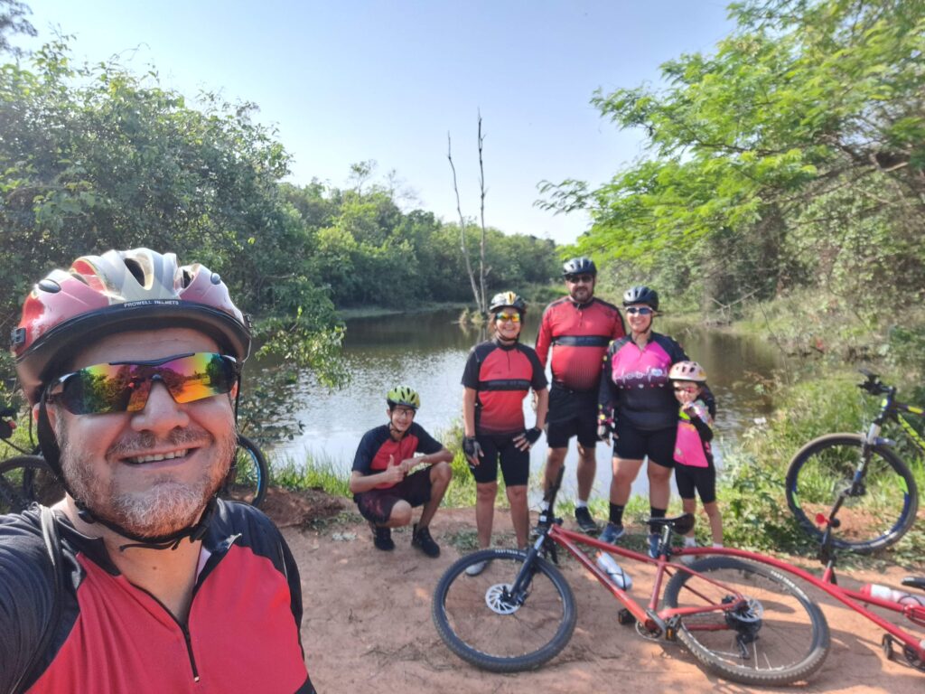 Integrantes do Grupo Baixa Pressão fazem uma selfie sorridente em frente à deslumbrante Lagoa do Bezerrão, celebrando sua jornada na Trilha do Bezerrão.