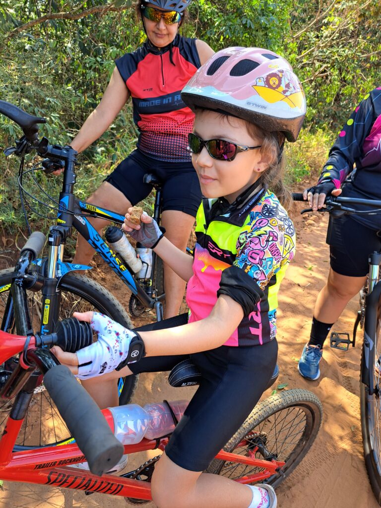  Laurinha, com um grande sorriso, relaxa em seu reboque e saboreia uma bolacha enquanto a trilha continua ao seu redor.