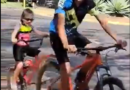 Joaozinho puxando Laurinha em um reboque de bicicleta