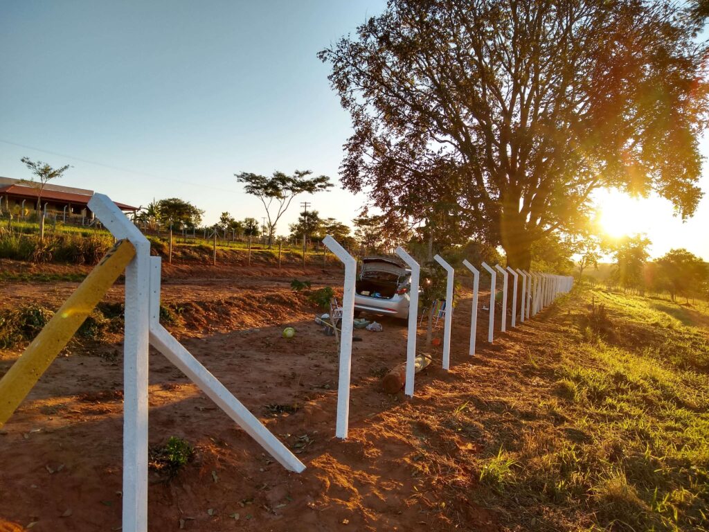 Construção de alambrado com um incrível pôr do sol ao fundo, destacando a harmonia entre o trabalho humano e a beleza natural.