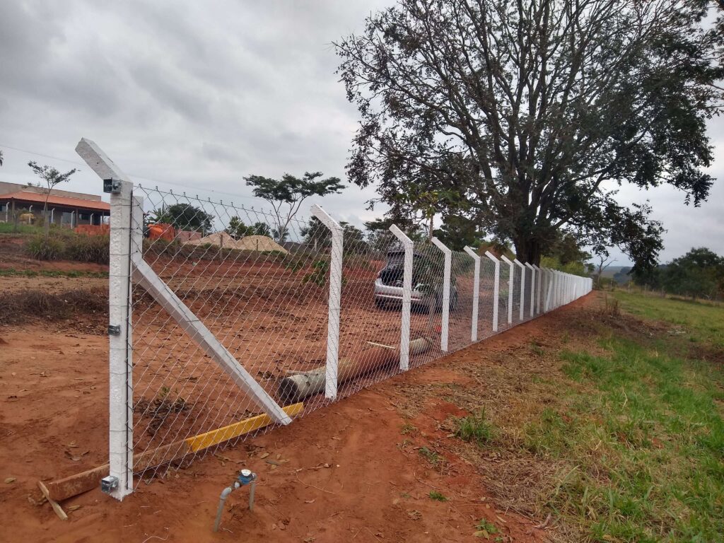 Vista angular a partir do primeiro poste da cerca de alambrado, destacando a linha reta formada pelo alambrado esticado ao longo do terreno. Isso demonstra a precisão na construção da cerca.