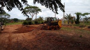 Máquina Bobcat em ação, nivelando e preparando o terreno para uso, demonstrando a eficiência na preparação de terrenos.