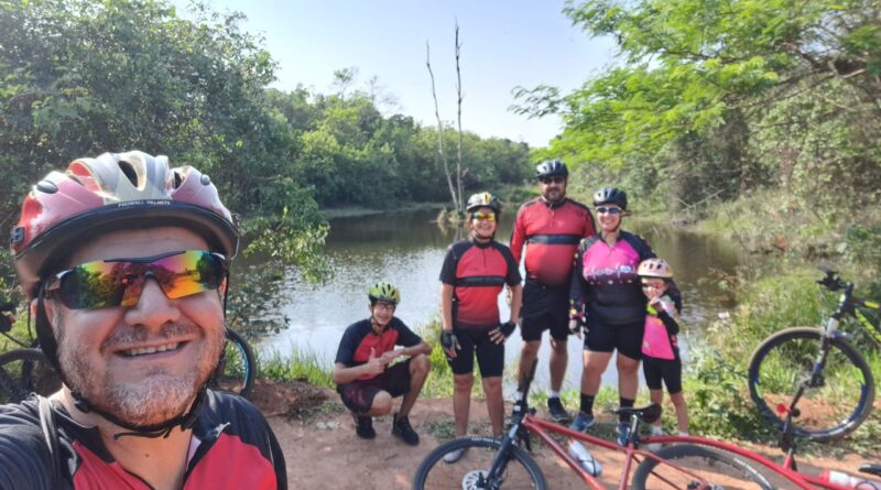 Integrantes do Grupo Baixa Pressão fazem uma selfie sorridente em frente à deslumbrante Lagoa do Bezerrão, celebrando sua jornada na Trilha do Bezerrão.